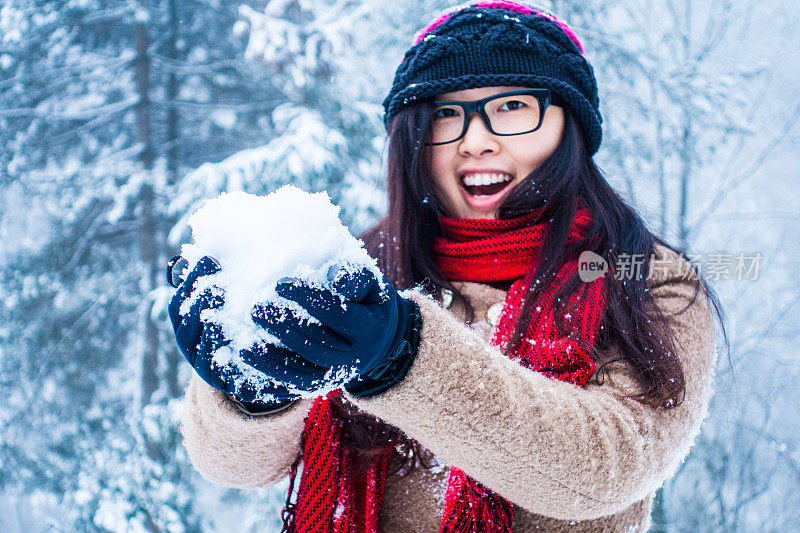 年轻女子在冬天的森林里玩雪