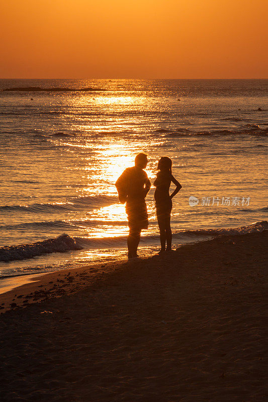 在海边散步的夫妇在日落时的剪影