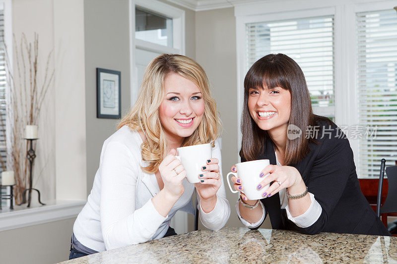 两个年轻女人坐在房子里喝着咖啡。