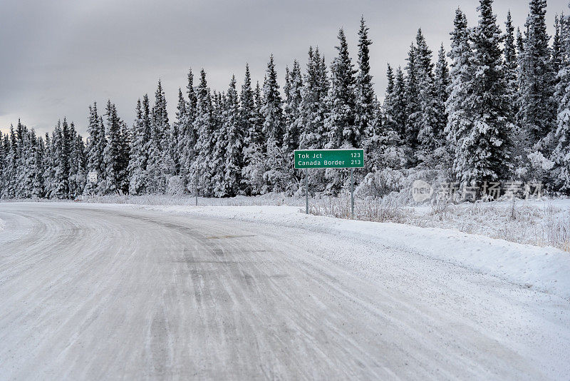 阿拉斯加冰雪覆盖的冬季道路与加拿大边境标志