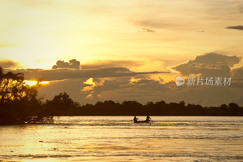 老挝湄公河上一艘小船后面的金色夕阳