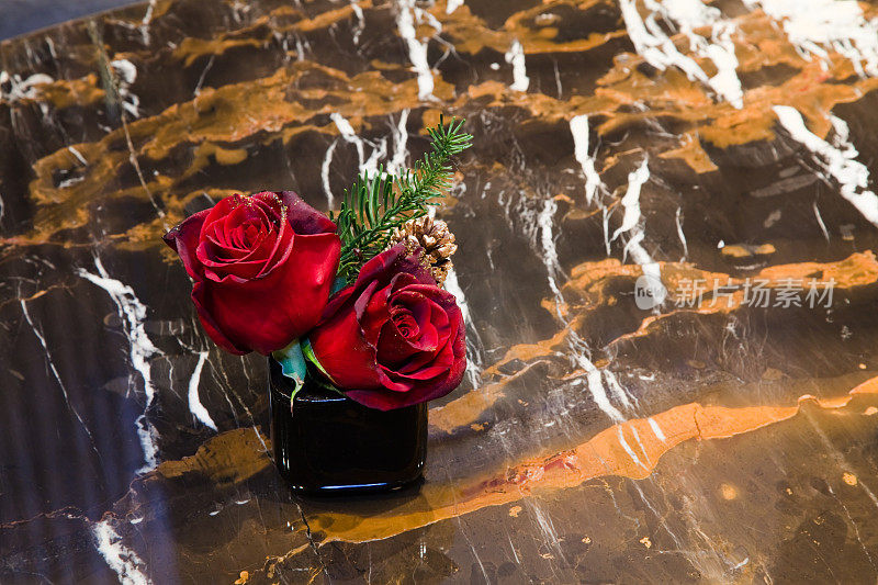 棕色大理石桌上放着两朵红玫瑰