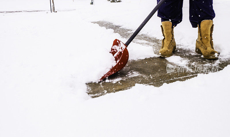 在暴风雪中从车道上铲雪的人