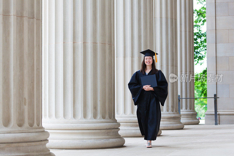 快乐的毕业女大学生横走在大学校园里