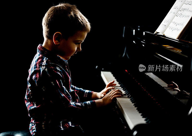 小男孩用乐谱弹钢琴