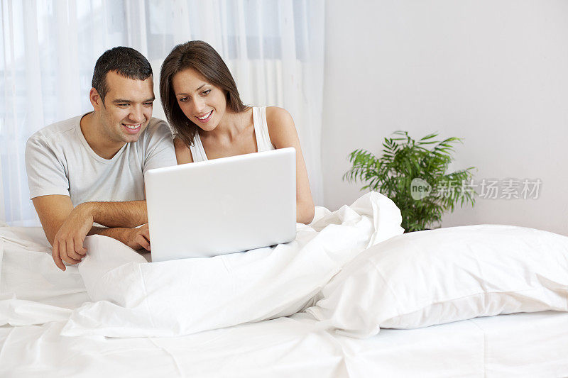 一对夫妇在床上玩笔记本电脑