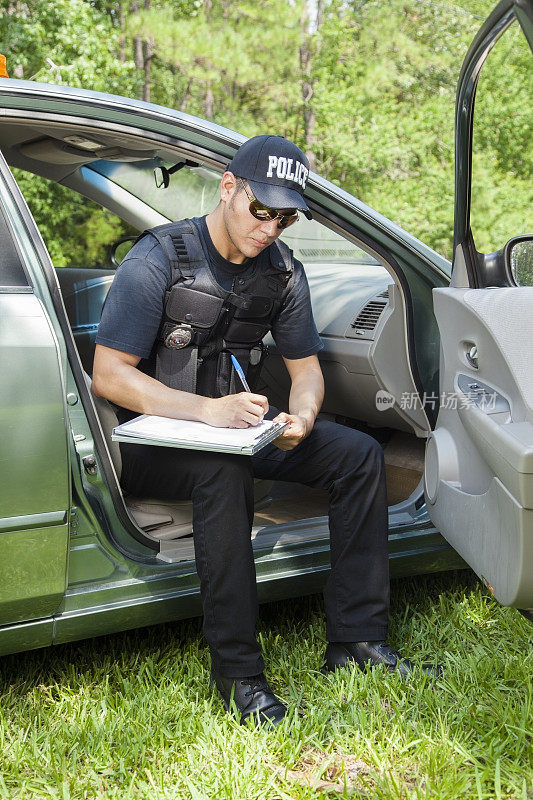 法律:拉丁警察在车上写事故报告。