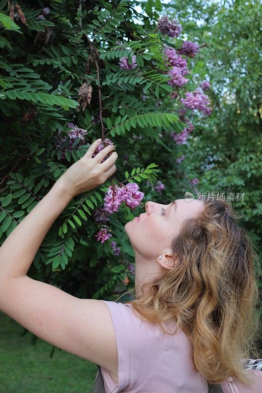 女人闻到刺槐的花香。