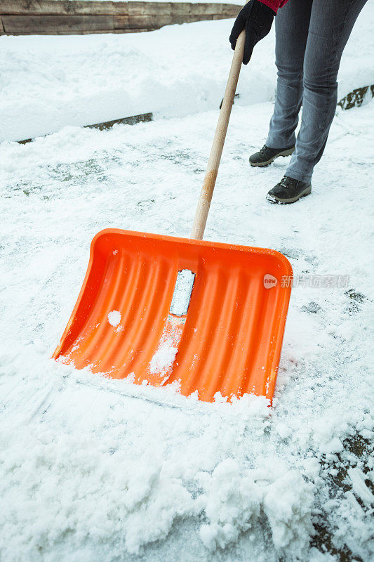 一位中年妇女正在清理屋前的积雪