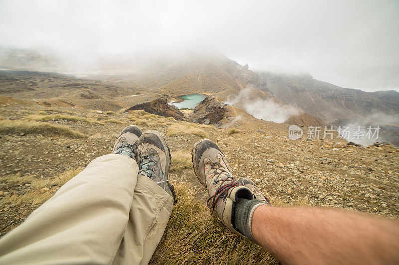 一对徒步旅行者坐在山上的湖边