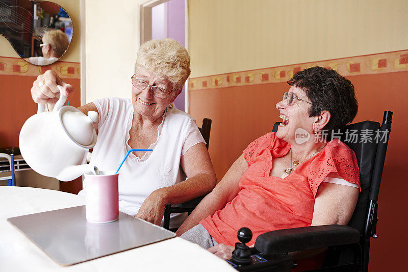 照顾者为快乐的残疾妇女沏茶