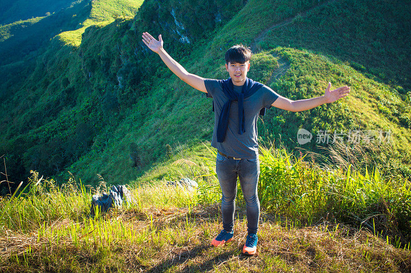 年轻的旅行者站在山上望着夕阳。