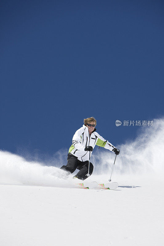 一名年轻人在粉雪中下坡滑雪