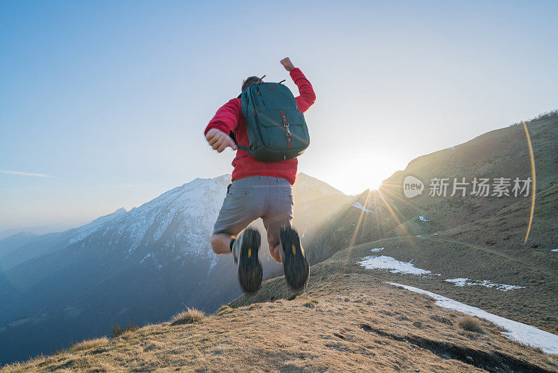 徒步旅行者在空中跳得很高，在山顶