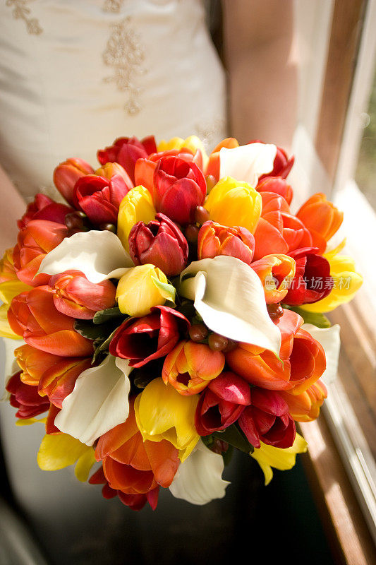 美丽的新娘捧着一束五彩缤纷的鲜花