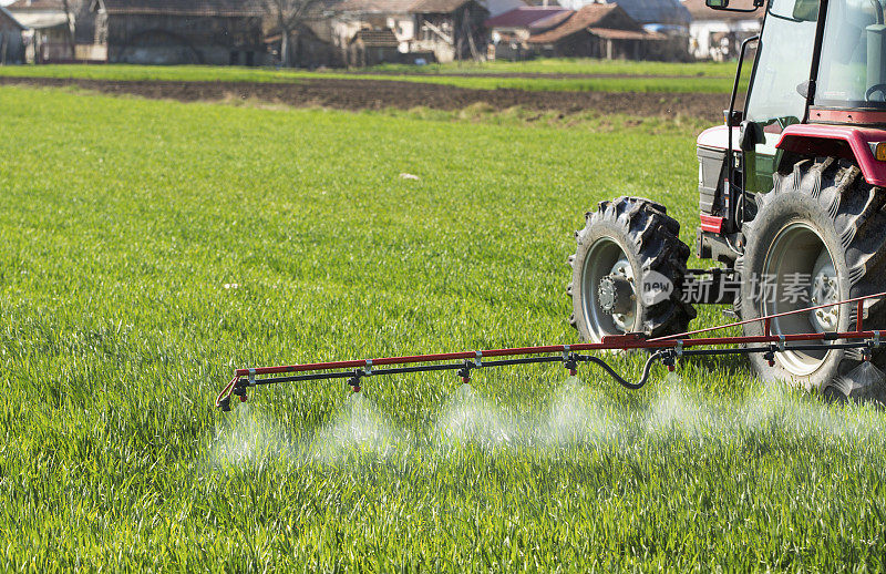拖拉机用喷雾器向麦田喷洒农药和除草剂