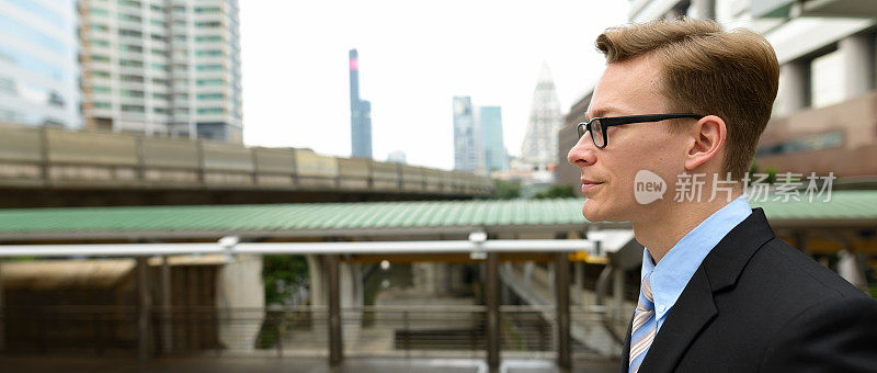 侧面的年轻英俊的商人戴眼镜反对曼谷的城市景观