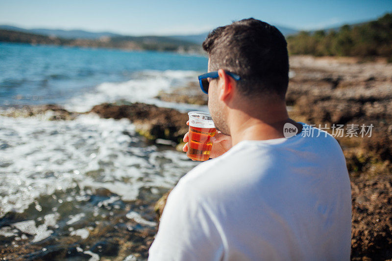 在海滩上喝啤酒的男人