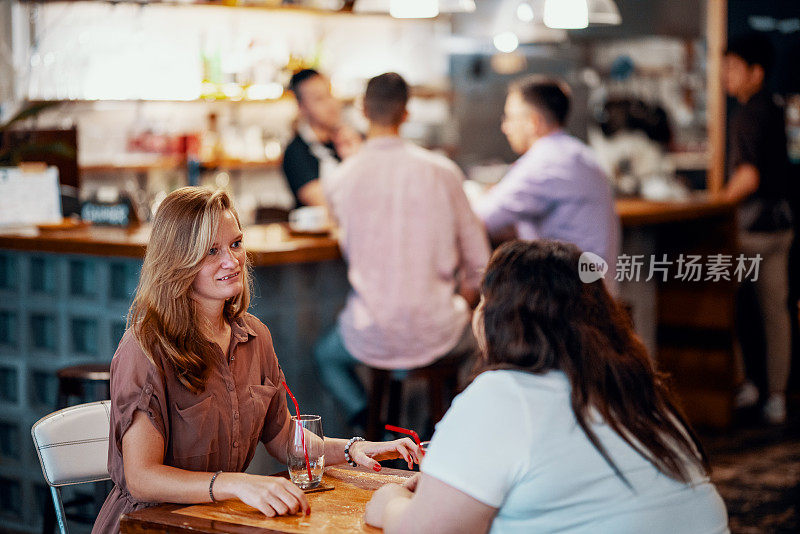 年轻女性白天坐在酒吧的桌子旁聊天