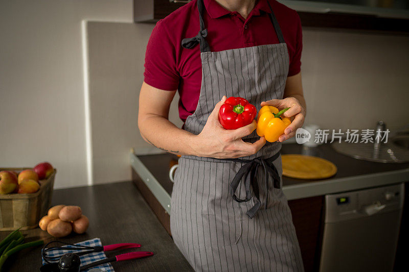 男人在厨房的桌子上切新鲜的春天蔬菜，特写。准备家庭食物，家庭厨房内部。