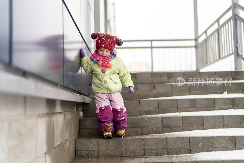 在一个大雪纷飞的冬日，小女孩心情不好地走在楼梯上。