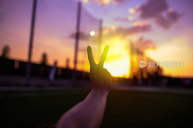 在美丽的夕阳下，手指的剪影做了一个和平的手势