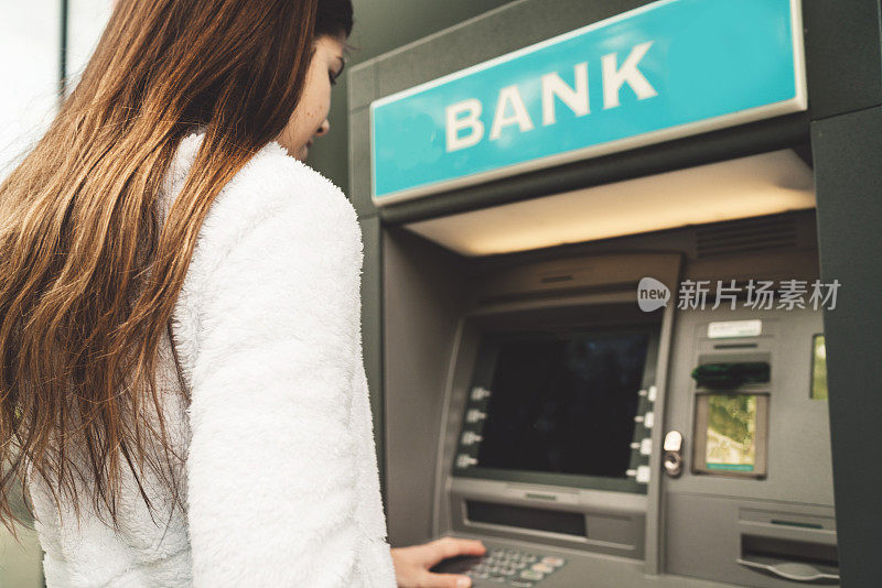 一个女人在自动取款机上取钱