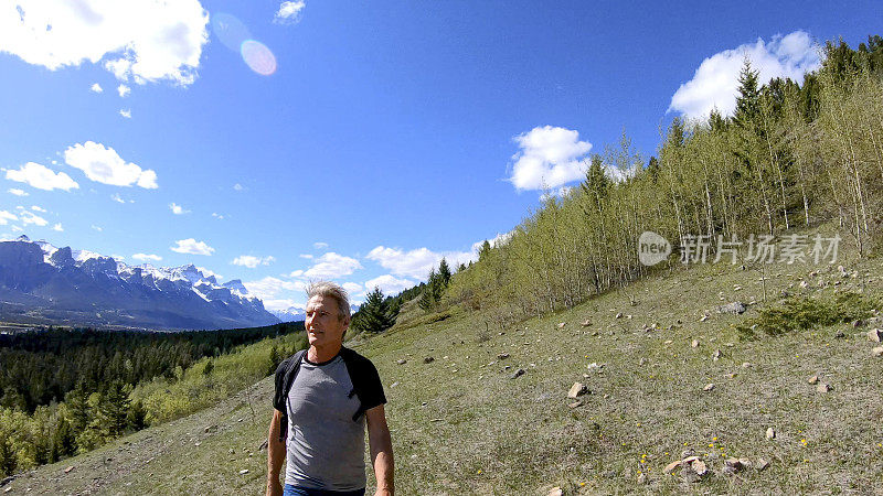 男人沿着长满草的山坡徒步旅行