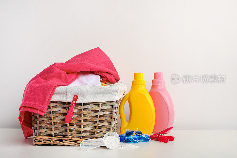 白色背景上有毛巾、洗涤剂、肥皂和竹球的洗衣篮