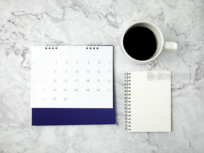 日历与一个咖啡杯和笔记本大理石纹理的背景