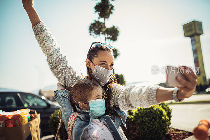 带着女儿戴着防护面具购物的女人