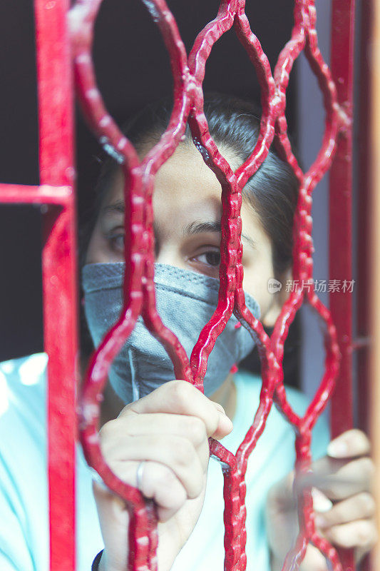 这个悲伤的女孩正在保护自己，戴着口罩，在家里自我隔离。