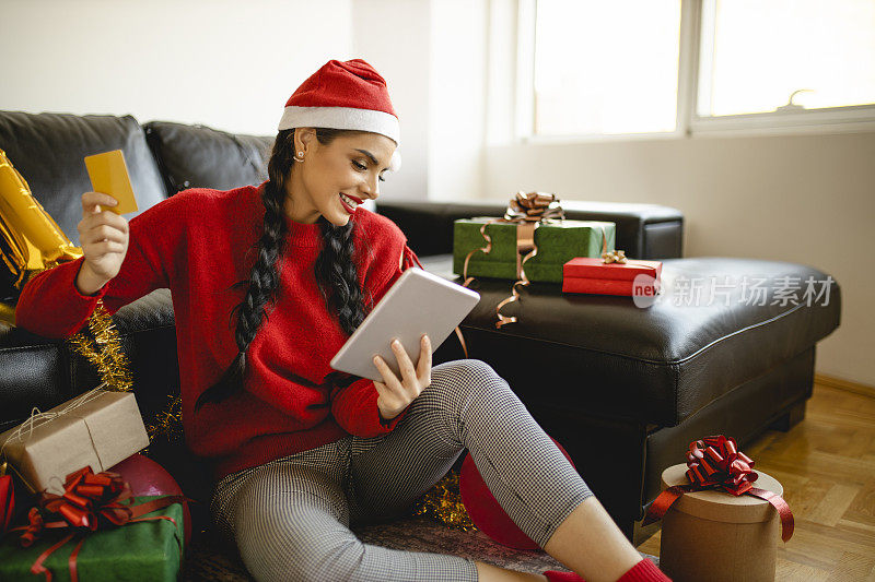 美丽的女人庆祝圣诞节和购物的圣诞礼物在网上在家