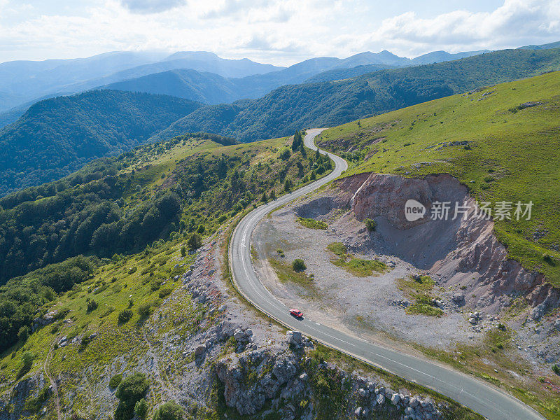 鸟瞰图，无人机在蜿蜒的山路上追赶快速行驶的红色汽车