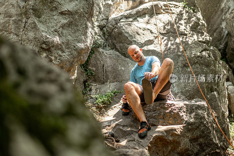 男性登山者坐在岩石山旁边的岩石上