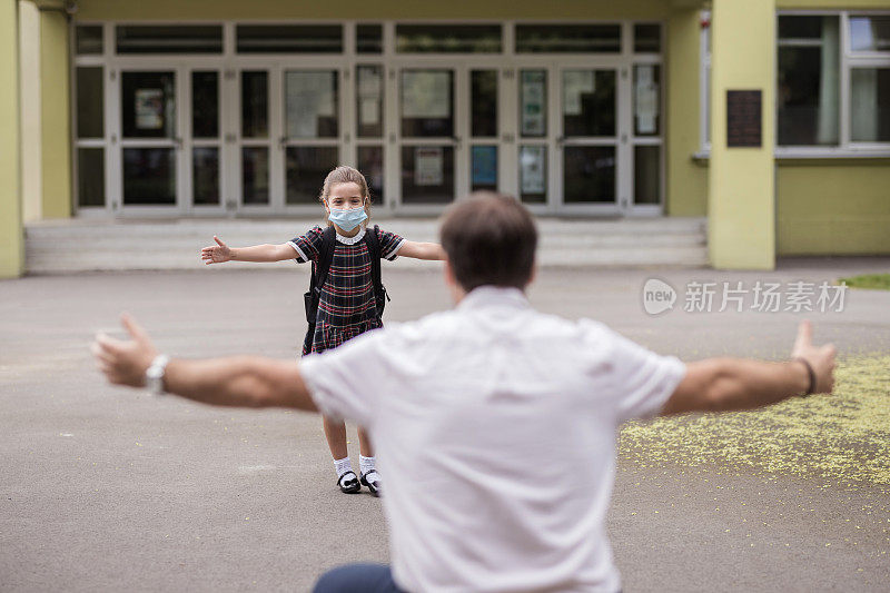 放学后，女孩戴着防护口罩摊开双手朝爸爸跑去