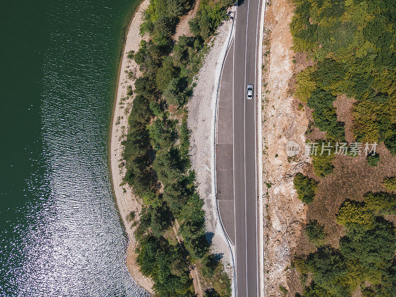 山里的空中公路旅行。忙碌的生活，俯视图，乡村道路经过旁边的山湖。