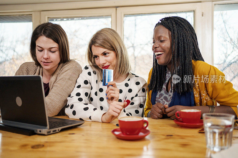 美丽的年轻女子多民族妇女在网上购物的咖啡馆