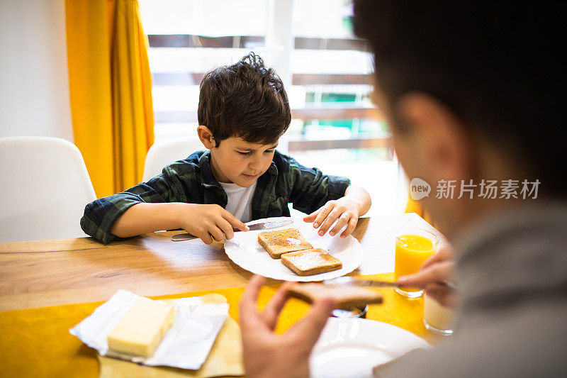 一个男孩在一片吐司上涂黄油