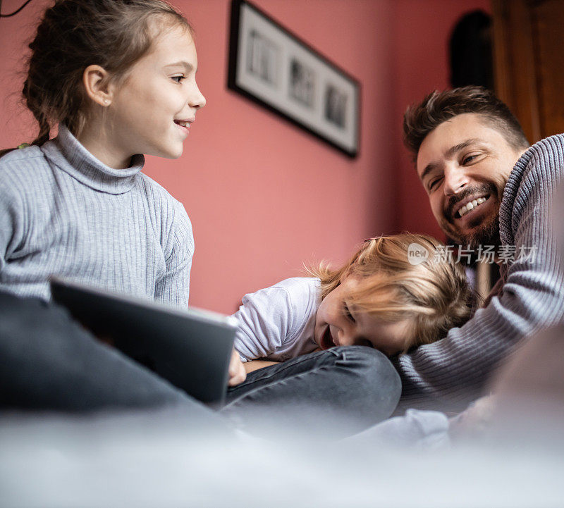 单身年轻父亲和他的女儿在家里用电子平板电脑看书