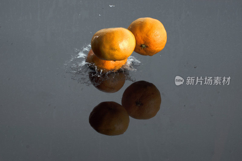 橘子掉进水里。水溅的背景。