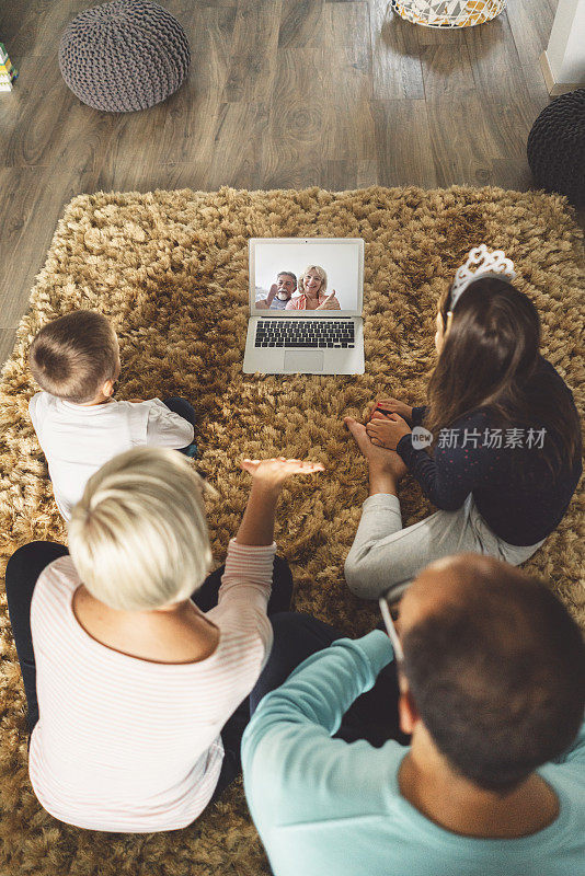 一家四口在平板电脑上与祖父母进行视频通话