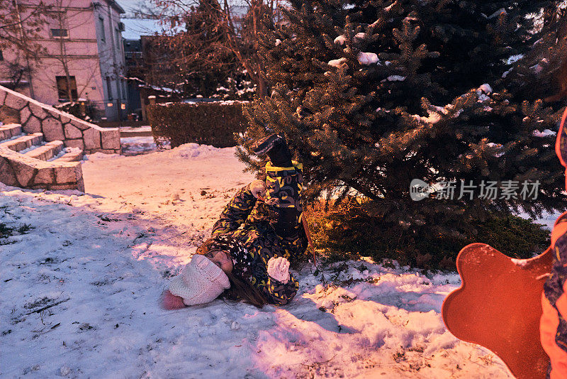 在她在雪地上滑行的时候，有趣的女孩从她的滑梯上掉下来，撞到一棵松树上