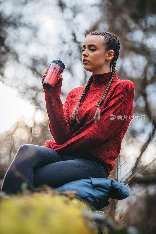 一个美丽的年轻女子坐在树林里的一棵树上的肖像