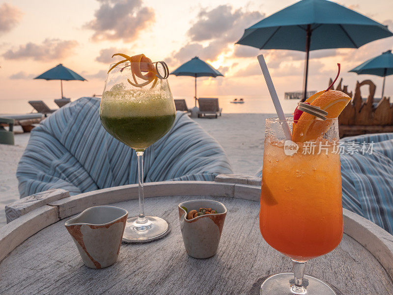 日落时分在海滩上喝两杯热带鸡尾酒