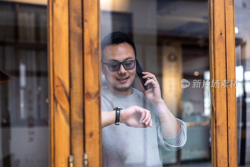 亚洲商人在一家咖啡馆的窗口打电话