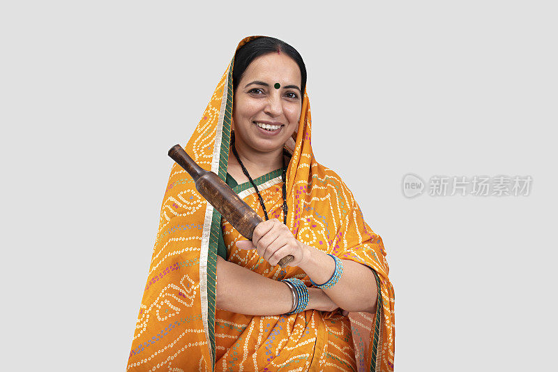 印度妇女的肖像在纱丽拿着擀面杖孤立地站在白色的背景