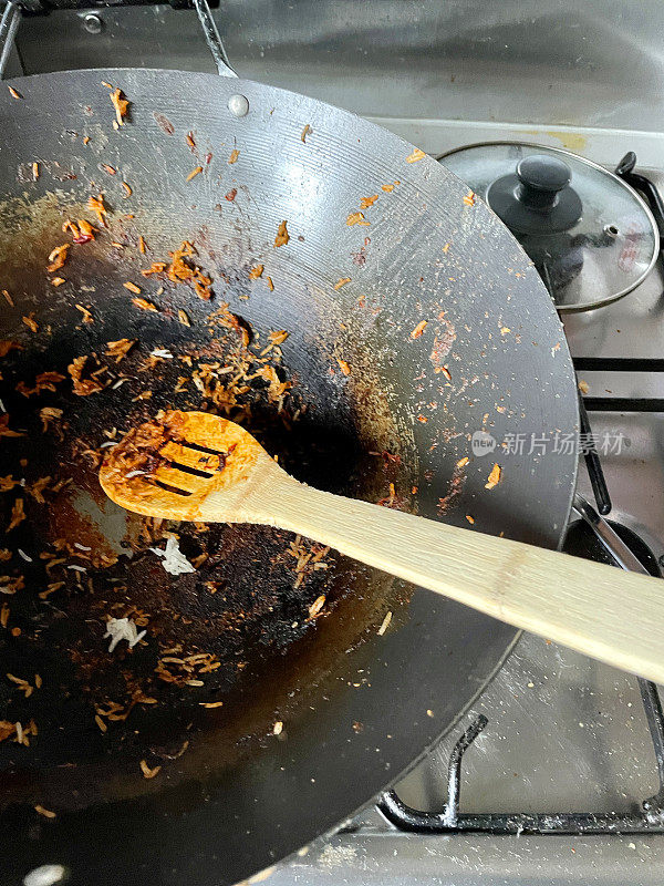 木勺在空锅上覆盖着烧焦的食物，煎锅坐在煤气灶上，俯瞰