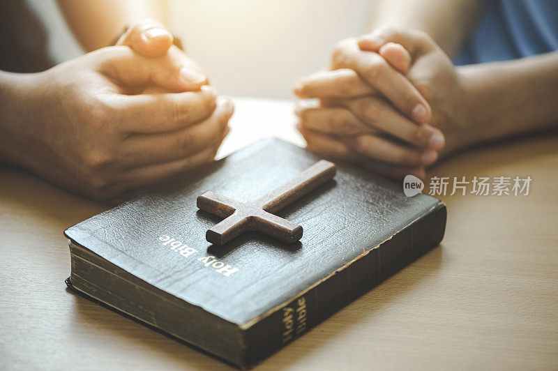 基督徒团体手放在木桌上，用圣经祷告神的祝福。乞求宽恕，相信善良。基督徒的生命危机祷告与敬拜神。