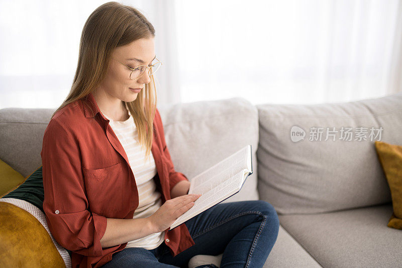 年轻女子正在家里看书。